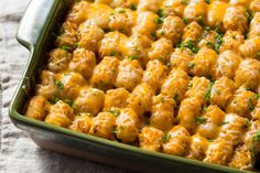 a green casserole dish filled with cheesy tater tots