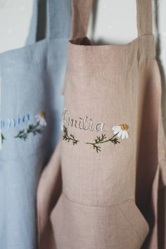 three bags with embroidered words and flowers on them