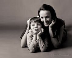 a woman and child laying on the floor posing for a black and white photo together