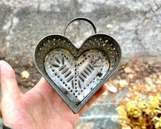 a heart shaped metal object held in someone's hand