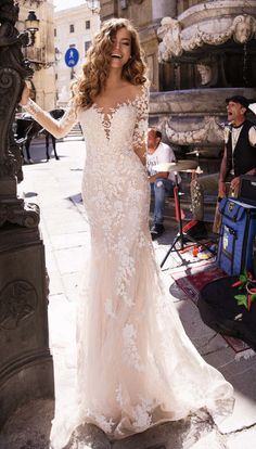 a woman in a wedding dress standing next to a lamp post on a street corner