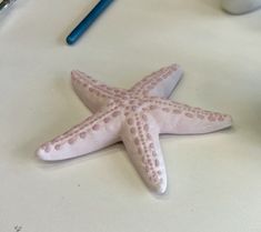 a pink and white starfish sitting on top of a table next to a cup