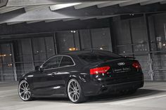 the rear end of a black car parked in a parking garage