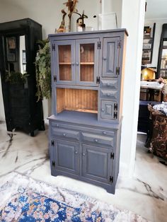 a blue china cabinet sitting in the middle of a living room next to a rug