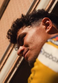 a close up of a person wearing a yellow shirt and holding his head in his hands