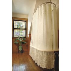 a white curtain in front of a stained glass window with wood flooring and potted plant