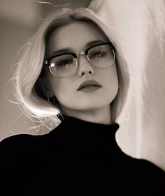 black and white photo of a woman with glasses looking off to the side while wearing a turtle neck sweater