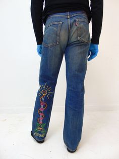 "These are a really unique pair of vintage 1970's hippy jeans.  These haven't been altered since the 70's when someone customized them and stitched some cool designs on them.  These are vintage Red line levi's.  According to our model, they feel like \"a 31'' waist and a 31'' length.\"  The tag says: 38 X 34.  This is really not true at all for today's sizes.  When we put a tape measure across the waist it is: 16'' across. 30'' actual inseam measurement  10'' across thigh measurements 7 3/4'' across base of leg measurement  These do show signs of wear, use, there is some staining pointed out.  I have quite a bit more photos of these, if you are interested in purchasing and would like to see more photos, please let me know and I will be glad to send them to you. Shipping: FED EX Ground with Hippie Fitted Denim Jeans, 70s Embroidery Jeans, Vintage Embroidered Denim Blue Bottoms, 70’s Panel Jeans, Hippie Jeans, Tape Measure, When Someone, Levi Jeans, Embellishments