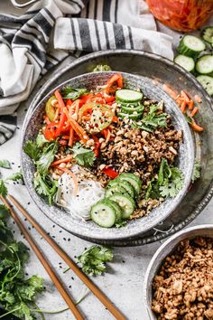 a bowl filled with rice, cucumber and carrots next to chopsticks