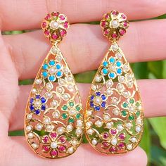 Featuring a pair of classy and contemporary, intricately carved jadau earrings in gold plated silver with multicoloured stones. The earrings are a breeze to wear, weighing just about 12 gms for the pair. The earrings' closure mechanism is perfect no-play bombay screw. All of Rudradhan's Gold Plated Jewellery is made using 925 Silver, real freshwater pearls and high quality ruby, emerald and sapphire beads. The default choice for studded stones used is synthetic that closely resemble original gem