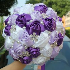 a bridal bouquet with purple roses and pearls on the bride's wrist is being held in front of a car