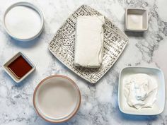 some food is sitting on a table with bowls and sauces around it, including marshmallows