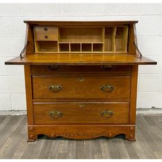 an old fashioned wooden desk with drawers on the top and bottom drawer, in front of a white brick wall