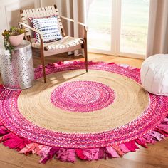 a round rug with pink fringes on the floor in front of a chair and window