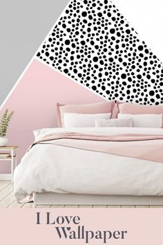 a bed with pink sheets and pillows in front of a black and white wallpaper