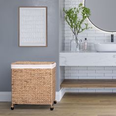 a bathroom with a sink, mirror and wicker basket on the floor next to it