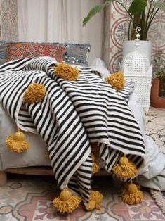 a black and white striped blanket with yellow pom poms