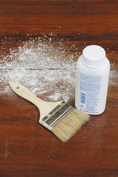 a wooden table topped with white powder and a paint brush on top of the table