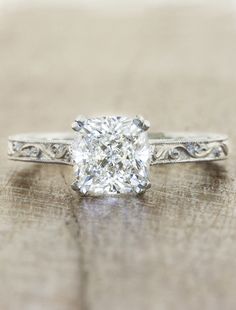 an old - fashioned engagement ring with a cushion cut diamond in the center and filigree band