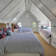 two beds in a room with white walls and blue and red striped bedding on them