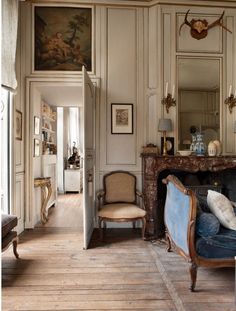 an old fashioned living room with antique furniture and paintings on the walls, along with wooden flooring