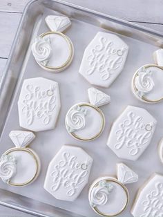 decorated cookies in the shape of wedding rings and engagement rings on a cookie sheet with icing