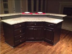 a kitchen island with granite counter tops in the middle of a wood floored room