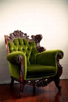 a green chair sitting on top of a wooden floor next to a white brick wall