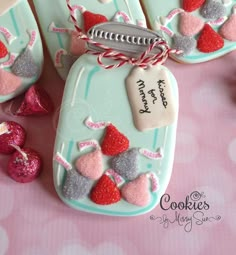 decorated cookies are sitting on a table next to pink and silver candies with tags