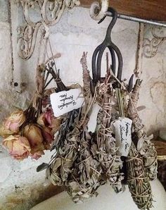 a bunch of scissors hanging from a hook on a wall next to some dried flowers