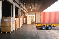 a large yellow truck parked in front of a building with lots of boxes on the ground