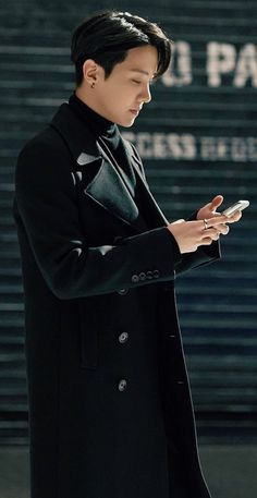 a man in a black coat looking at his cell phone