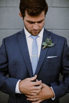 a man in a suit and tie is holding his hands together