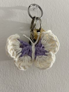 a crochet butterfly keychain hanging from a hook on a white wall