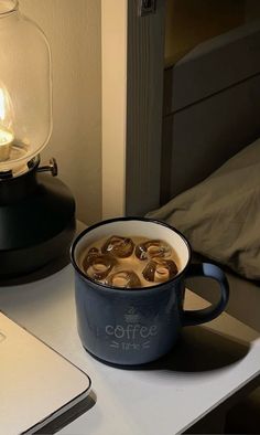 a cup of coffee sitting on top of a table next to a laptop