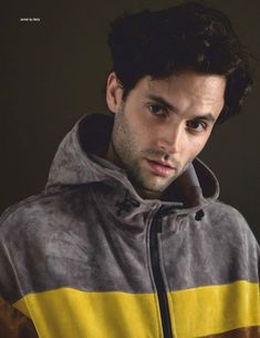 a young man in a yellow and grey jacket looking at the camera with serious look on his face