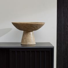 a bowl sitting on top of a black cabinet next to a white wall and door