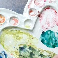 an artist's palette with paint and watercolors on it