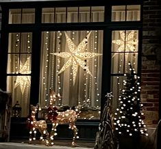 lighted christmas decorations in front of a window with lights on the windowsill and reindeer figurines