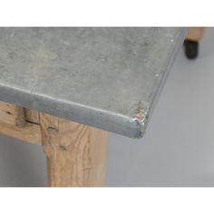 an old metal table sitting on top of a hard wood floor next to a gray wall