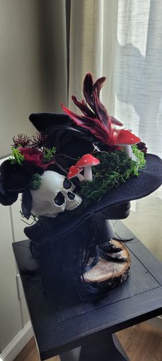 a black hat with red and white flowers on it sitting on top of a table