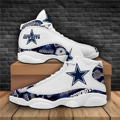 a pair of white and blue shoes with the cowboys logo on them sitting on top of a box