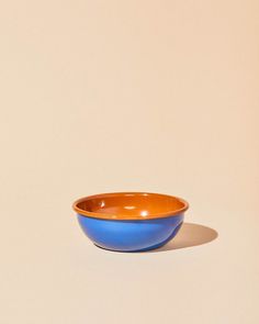 an orange and blue bowl sitting on top of a white countertop next to a brown wall