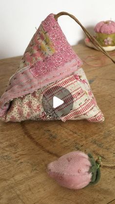 a piece of fabric sitting on top of a wooden table next to a pink flower