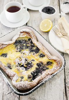 a pan filled with blueberries and powdered sugar on top of a wooden table