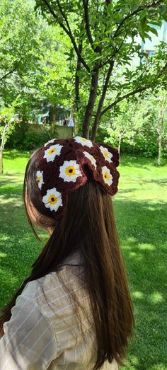 a woman wearing a crocheted headband with daisies on it in the grass