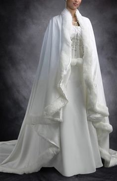 a woman wearing a white wedding gown and cape