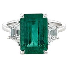 CDC certified Emerald cut Emerald weighing 4.16 carats Indications of minor clarity enhancement Measuring (12.05x8.05x5.80) mm Diamonds are E-Si2 quality Trapezoid diamonds weighing .88 carats Set in platinum ring 6.03 grams Smaragd Ring, Columbian Emeralds, Emerald Cut Diamond Ring, Platinum Diamond Rings, Emerald Diamond Ring, Colombian Emeralds, Stone Engagement Rings, I Love Jewelry, Emerald Jewelry