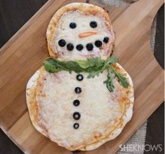 a pizza with a snowman made out of cheese and olives on it, sitting on a cutting board