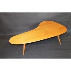 an oval shaped wooden table with two legs and a curved top, on a black background